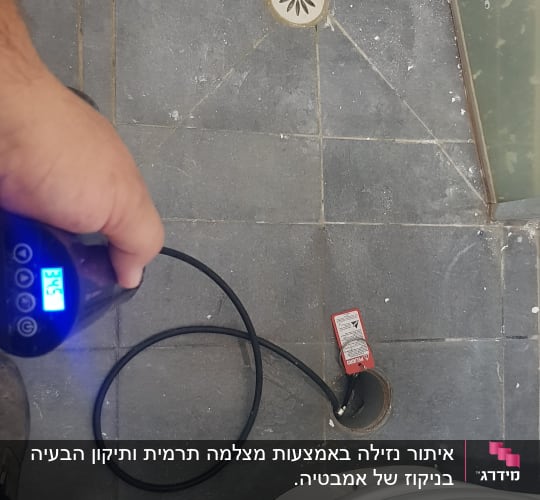 מכשיר מדידה עם צינור ליד פתח ניקוז ברצפה